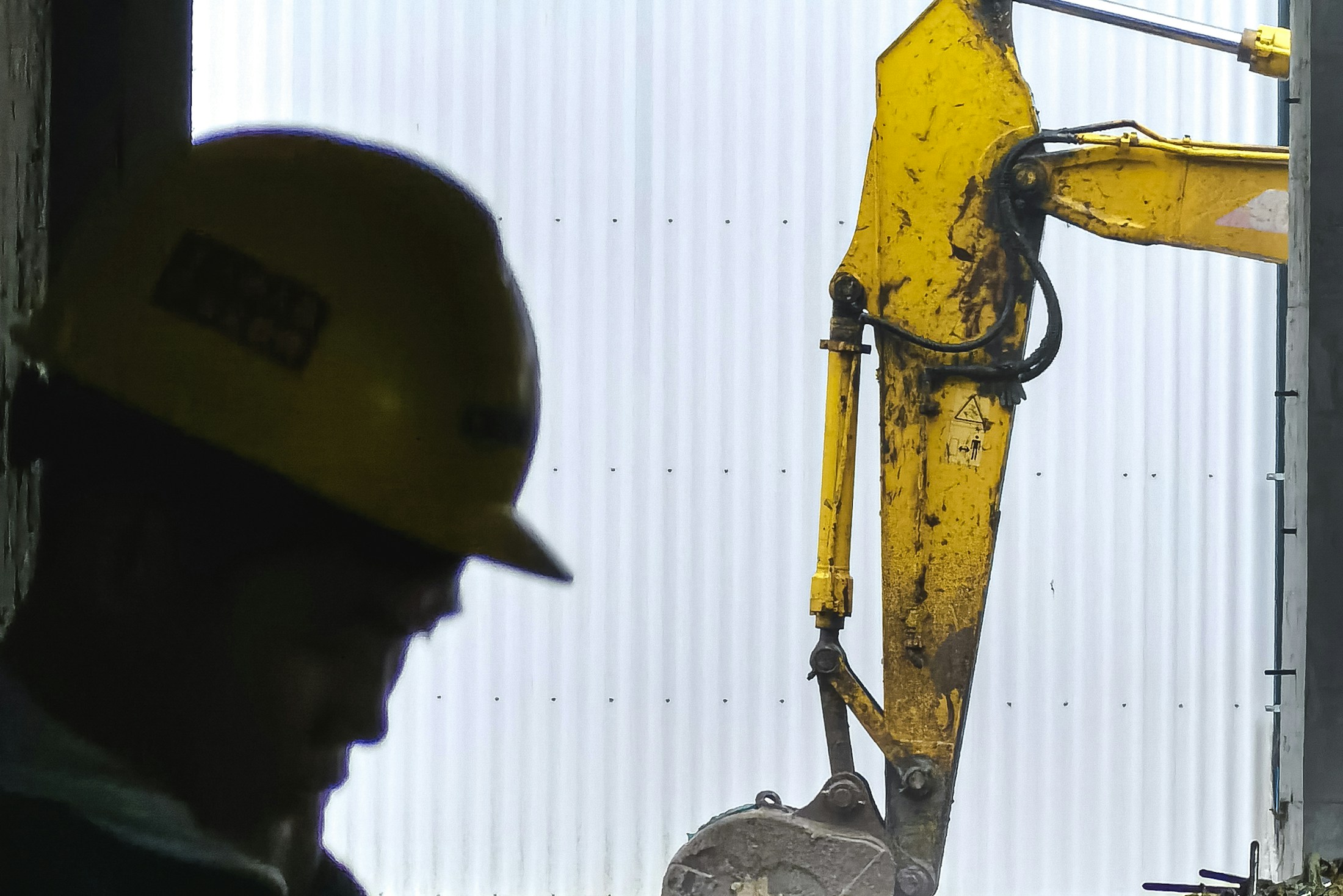Handwerker mit Schutzhelm arbeitet an einer Maschine, Sinnbild für digitale Auftragsabwicklung im Handwerksbetrieb
